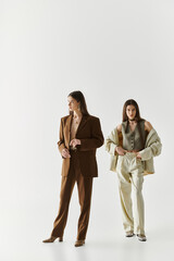 Stylish twin sisters showcase modern fashion in a minimalistic studio setting