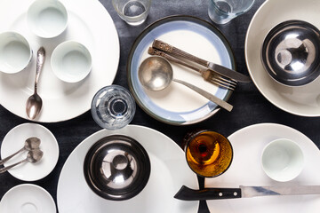 Top view of an empty plates, bowls, glasses and cutlery placed on a black chalkboard background. Flat lay. Top view. Food concept.