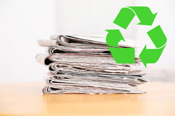 Recycling symbol and stack of many newspapers on wooden table, closeup. Eco-friendly lifestyle,...