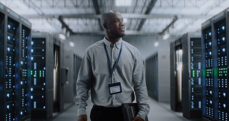 Fototapeta premium Big Data Center with Server Racks: Professional African American Specialist with Tablet Computer Walking In Warehouse. Internet Servers, Information Technology, Cyber Security and Telecommunications.