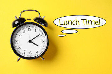 Alarm clock and speech bubble with words Lunch Time on yellow background