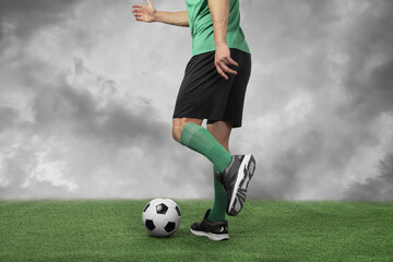 Football player kicking soccer ball under cloudy sky, closeup