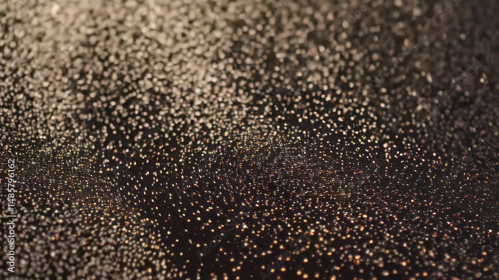 Sticker abstract surface with shifting bokeh lights and golden glitter particles flowing gently into the dar
