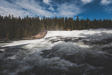 summer clear day in Wells Gray Provincial Park. scenic views of wide and high waterfalls in a outdoor andventurous trip. splashing water, intense green and high contrast light all around