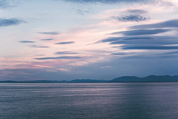 on the road to vancouver island on a summer roadtrip. mountains, clouds, boats and wild animals ad a dreamy pastel sunset on a cloudy evening