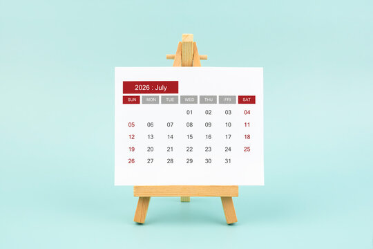 Calendar page for July 2026 with wood easel on a blue background.