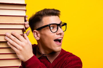 Excited Young Man Holding book Against Yellow Background Displaying Happiness and Energy