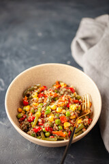 Vegetables corn quinoa salad in clay bowl.