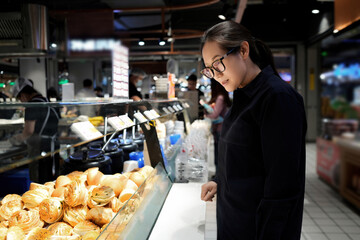Woman Browsing Bakery Items in a Modern Food Court