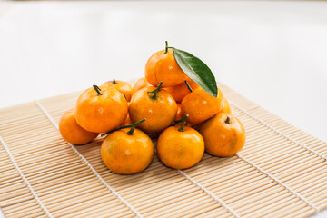 Mandarin oranges arranged in a white square container on top of sushi rolls on a white table