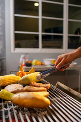 A man enjoys a summer barbecue outdoors, grilling meat and vegetables over open flames, surrounded by friends, smoke, drinks, and weekend freedom.
