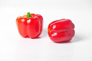 On a white background are two red peppers. The peppers are ripe and located next to each other.