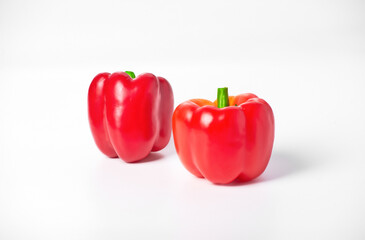 On a white background are two red peppers. The peppers are ripe and located next to each other.