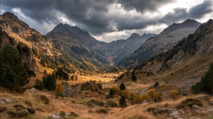 Obraz premium Majestic Autumn Landscape with Dramatic Mountains and Golden Valley under a Cloudy Sky