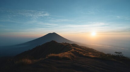 Majestic Sunrise Over Mountain Peak with Clear Blue Sky and Soft Clouds in a Serene Natural Landscape