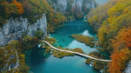 A peaceful morning in Plitvice, where a wooden path winds alongside a crystal-clear lake, framed by colorful autumn trees.