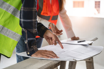 Fototapeta premium Concept Teamwork of building construction staff. Project engineer contractor reviewing plan of work with foreman and worker at construction site.