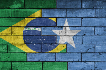 colourful painted big national flag of somalia and flag of brazil on a massive old brick wall background. concept