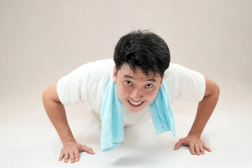 man performing push-ups in white clothes on a neutral background