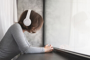 Back view of beautiful lonely sad сaucasian woman standing near window