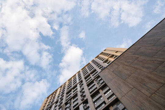 Bottom view of tall multi-story buildings against blue clody sky