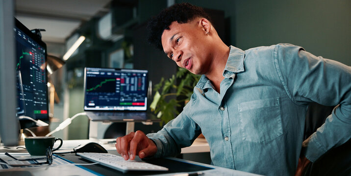 Man, back pain and computer screen with trading, stress and charts for market review in office at company. Person, spine injury and burnout at night, graphs and fatigue with statistics at agency