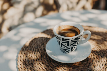 Cup of aroma black coffee a on a table in a street cafe in a sunny morning.