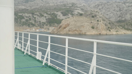 Ferry ship exterior deck white fence with coast in background