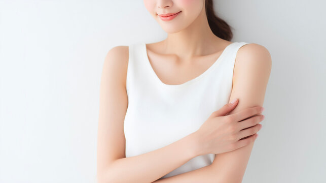 白い服の女性が自分の腕を優しく包む清潔感あふれるスキンケアイメージ（美容・エステ・脱毛・コスメ）