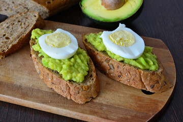Toast with mashed avocado and slice of Egg on a Wooden Board