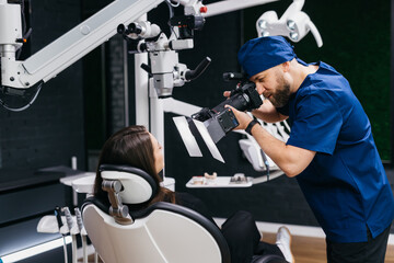 A dentist takes a photo of the result after treatment or cleaning of teeth of a young woman in a dental clinic. Concept of dental services and treatment.
