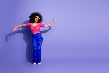 Stylish young woman showcases colorful retro fashion with vibrant outfit and joyful expression against a purple backdrop