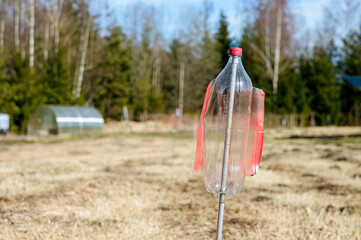 An empty upside-down plastic bottle with cut-off blades spins,vibrates and rattles in the garden,...