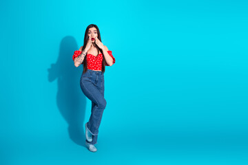 Stylish young woman in vibrant casual attire making a surprised hand gesture against a vivid blue background