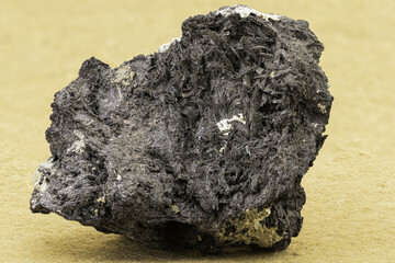 Dark mineral rock with fibrous texture and metallic reflections. Ideal for educational, geological, scientific or natural history themed visual content