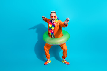 Cheerful mature man in bright orange suit enjoying a fun vacation vibe with a green float, making playful gestures
