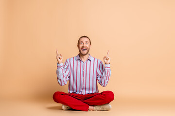Happy young man in stylish outfit gesturing and enjoying himself against a beige background