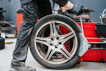 Mechanic repairing wheel on tire changing machine in auto repair shop