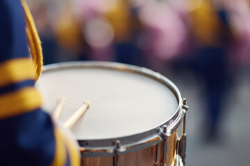 Marching band member playing snare drum with focus on drumsticks