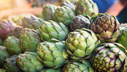 Obraz premium Close-up of fresh organic artichokes displayed at a local weekend market, showing texture, natural color, and freshness of seasonal vegetables.