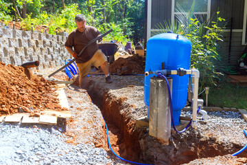 Worker actively pipe PEX laying to trench for artesian water well system installation