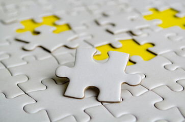 Obraz premium Close up of white jigsaw puzzle pieces placed on a bright yellow background with customizable space on jigsaw for text or ideas.