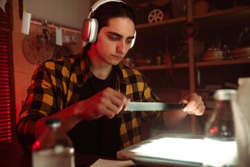 Young Man with Headphones Examining Camera in Retro Photography Studio