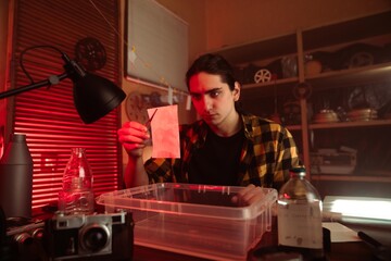 Young Photographer Developing Film In Darkroom Setting