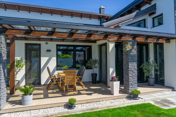 This image showcases a modern residential home with stylish outdoor seating, highlighting the elegant design and inviting atmosphere of the patio space on a sunny day