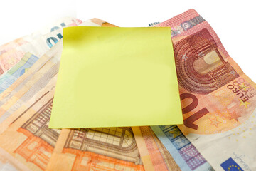 European banknotes on a white surface and yellow paper note on top. Monthly bill payments reminder for house rent, electricity, water and phone. Rising cost of living in Euro Union theme.