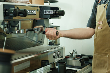 Adult male barista adjusting espresso machine with portafilter inside cafe, demonstrating artisan craft, precision, and dedication, reflecting charm of small family coffee business, small business