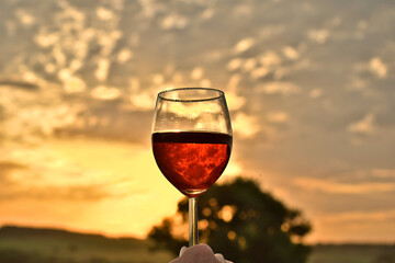 A glass of red wine against the sunset sky,