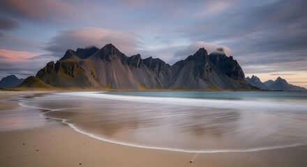 Obraz premium Mountains Reflecting on Sandy Beach at Dusk in Coastal Scene