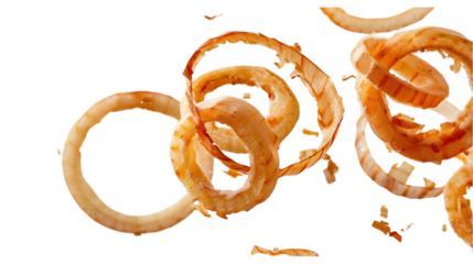 A close up shot of several onion rings and onion peels floating in the air on a black background